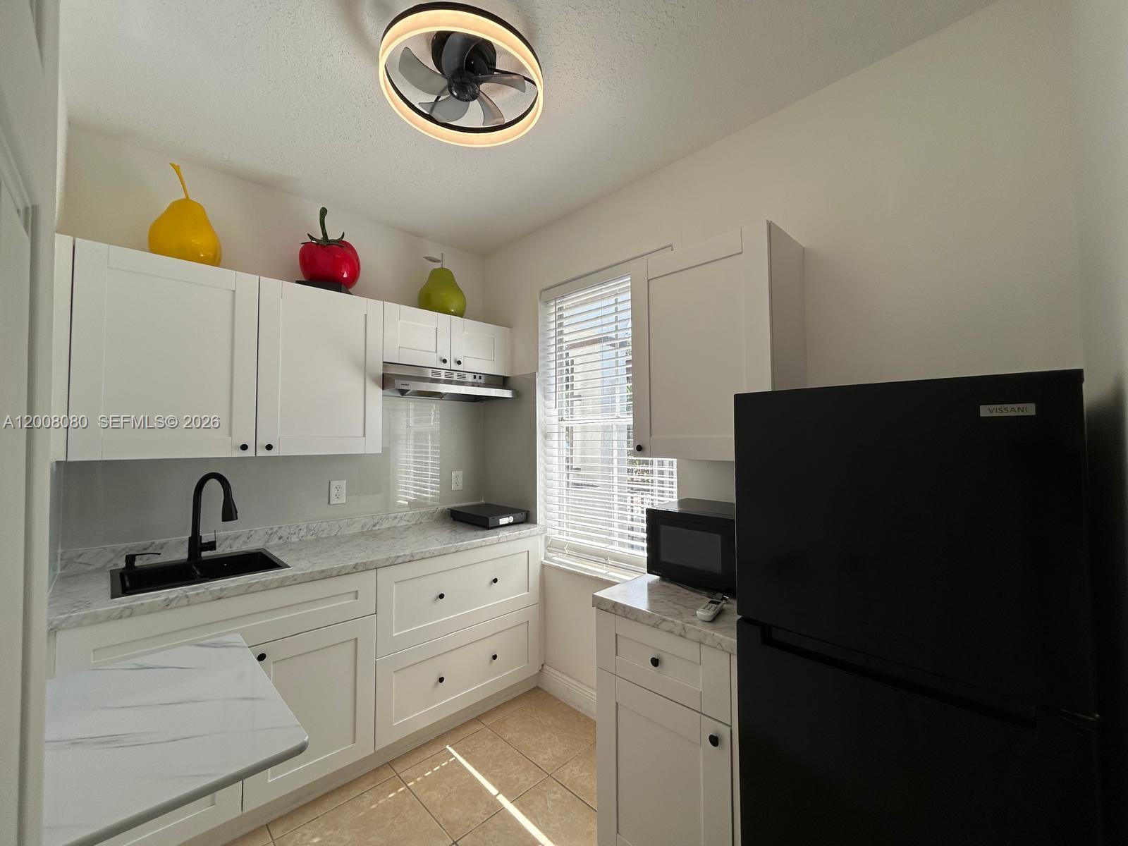 A small kitchen features white cabinets, marble-look countertops, a black sink, and a black refrigerator — 14731 SW 170th Ter # 1, Miami FL 33187, MIAMI, FL