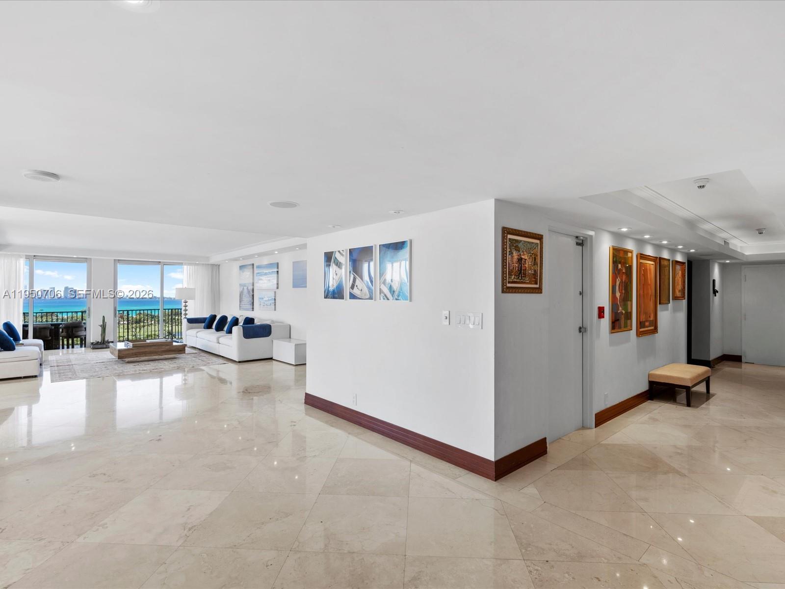 A spacious living room features marble floors, white walls, and a balcony with ocean views — 5660 Collins Ave # 18A, Miami Beach FL 33140, MIAMI BEACH, FL