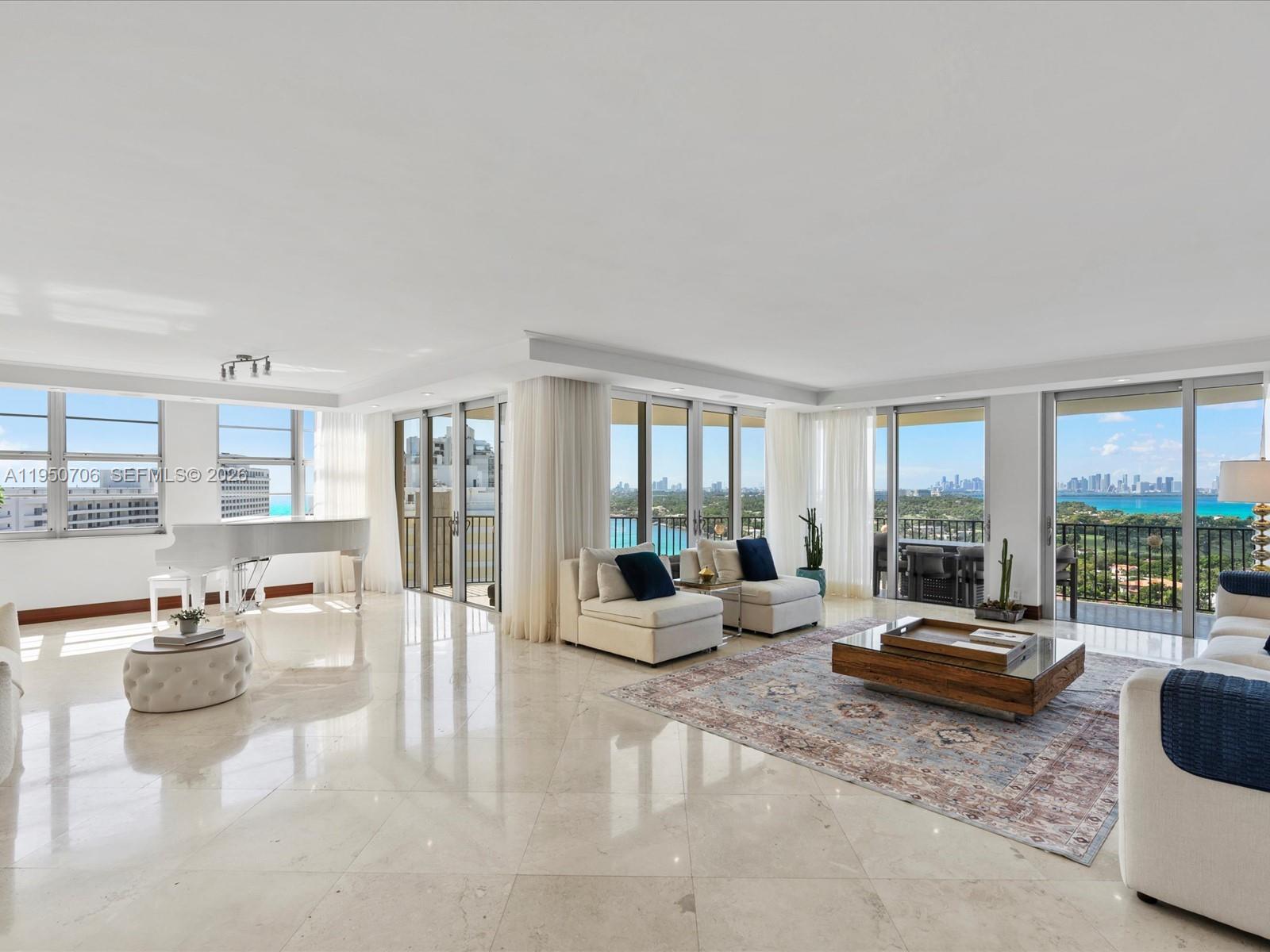 A spacious living room features marble floors, a white grand piano, and floor-to-ceiling balcony windows — 5660 Collins Ave # 18A, Miami Beach FL 33140, MIAMI BEACH, FL