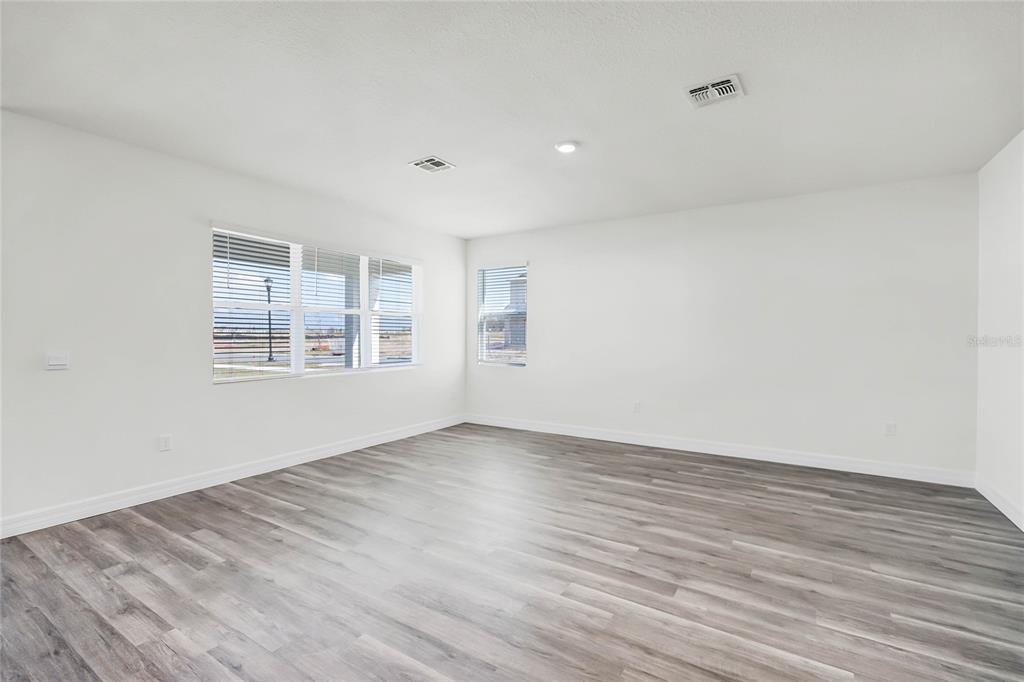 An empty room with white walls, gray wood-look flooring, and several windows — 5231 LIGONBERRY STREET, LAKELAND, FL
