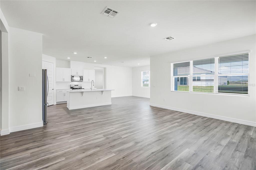 An open-concept kitchen and living area features white cabinetry, a center island, and wood-look flooring — 5231 LIGONBERRY STREET, LAKELAND, FL