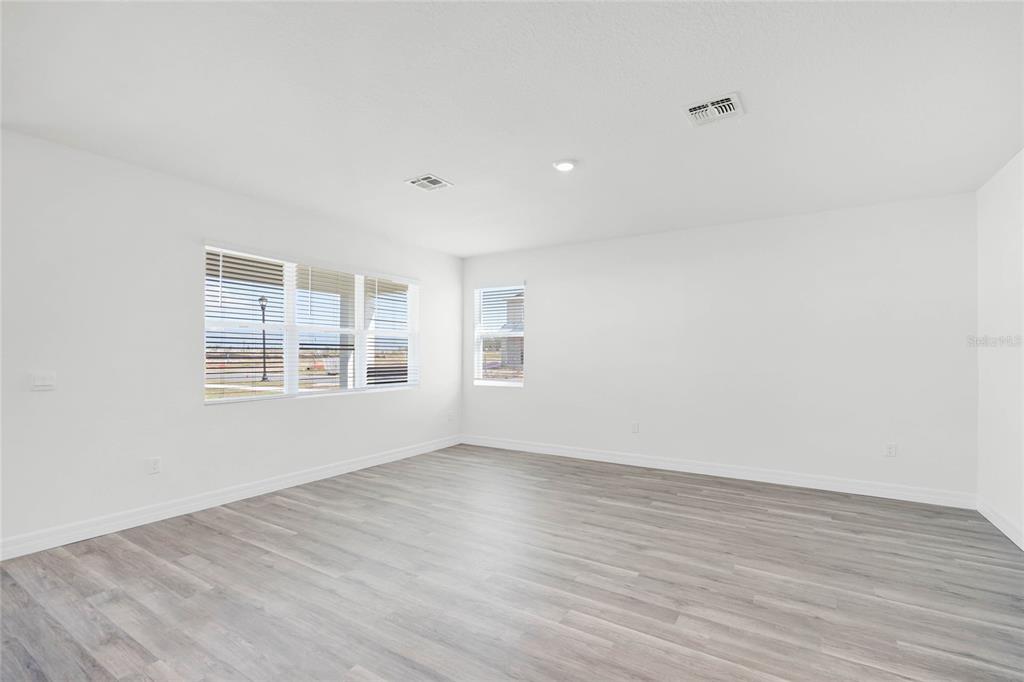 An empty room with white walls, light wood-look flooring, and windows with blinds — 5231 LIGONBERRY STREET, LAKELAND, FL
