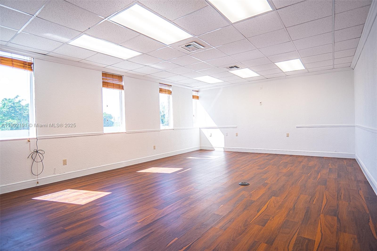 An empty office space features white walls, a drop ceiling, and dark wood-look flooring — 3401 NW 7th St, Miami FL 33125, MIAMI, FL