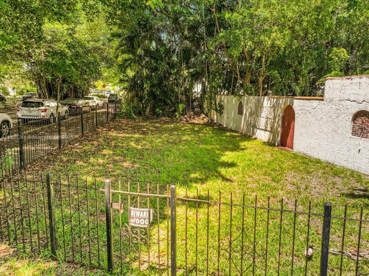 An empty, grassy lot is enclosed by a metal fence and a white stucco wall — 5900 NE 5th Ave, Miami FL 33137, MIAMI, FL