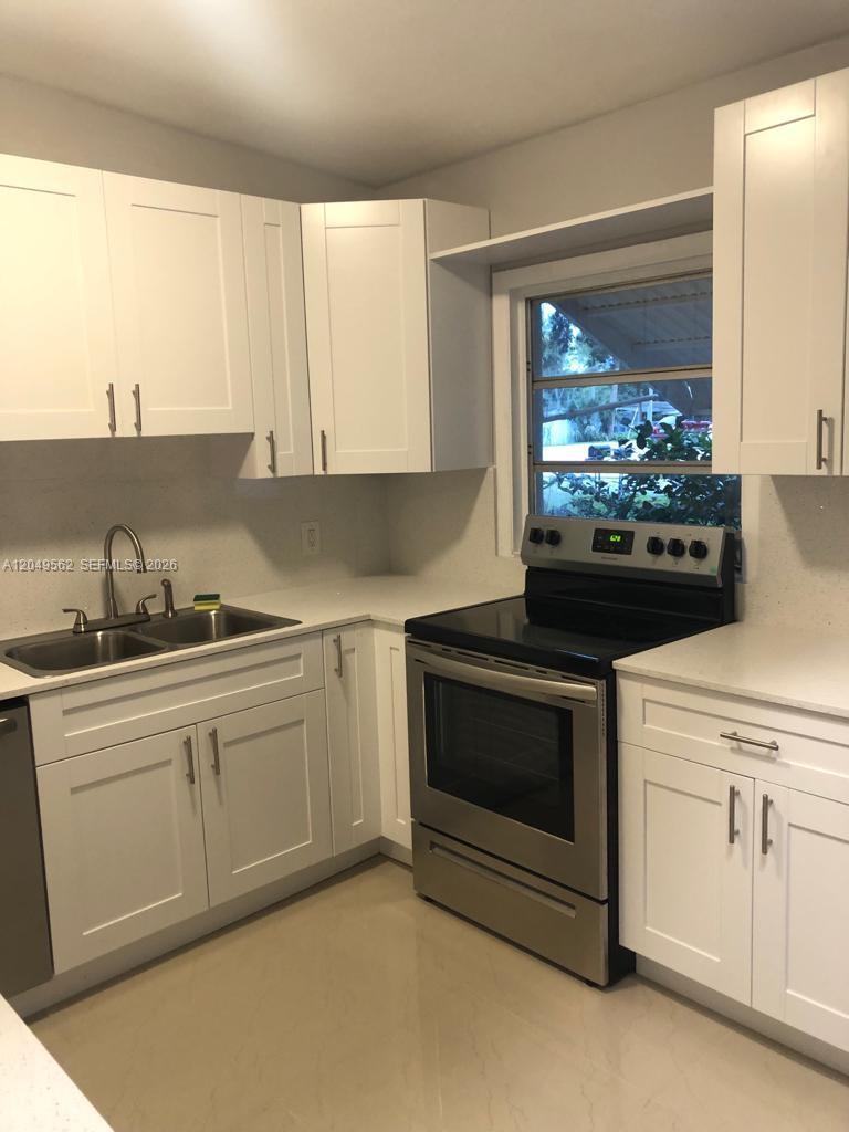 A kitchen features white shaker cabinets, stainless steel appliances, and light-colored countertops — 2106 79th CT # A, Vero Beach FL 32966, VERO BEACH, FL