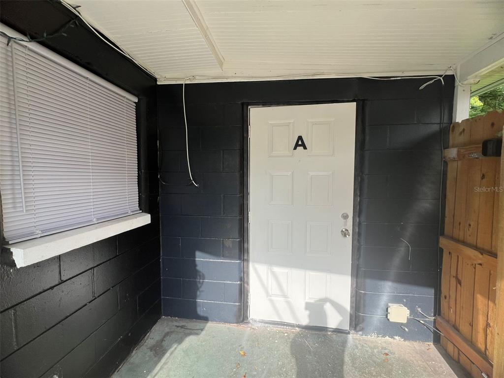 A white door labeled A is set into a black painted concrete block wall — 3407 N AVENIDA REPUBLICA DE CUBA UNIT A, TAMPA, FL