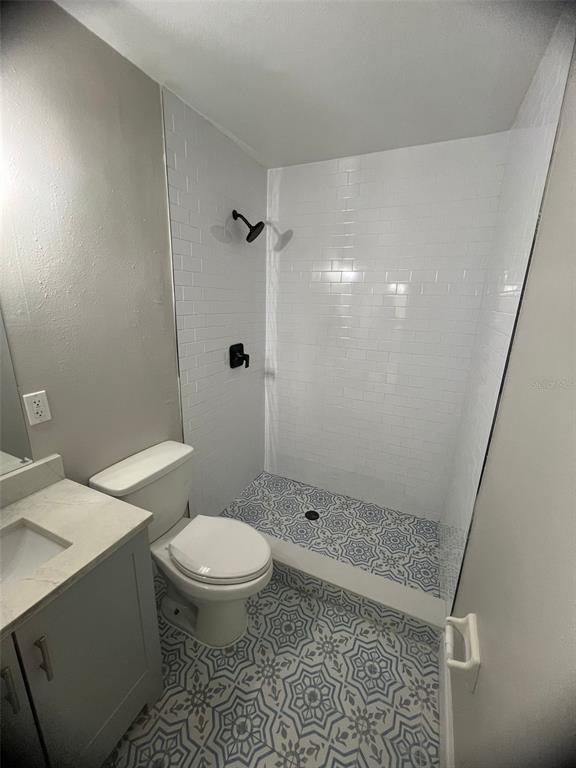 A bathroom features a vanity, toilet, and a walk-in shower with patterned tile flooring — 3407 N AVENIDA REPUBLICA DE CUBA UNIT A, TAMPA, FL