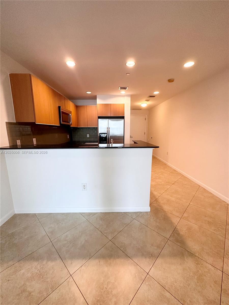 This kitchen features wood cabinets, stainless steel appliances, and a black countertop breakfast bar — 1060 Brickell Ave # 2515, Miami FL 33131, MIAMI, FL