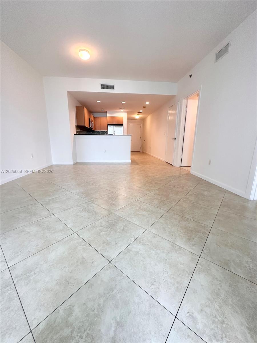 This interior view shows an open-concept living area with tile flooring leading to a kitchen — 1060 Brickell Ave # 2515, Miami FL 33131, MIAMI, FL