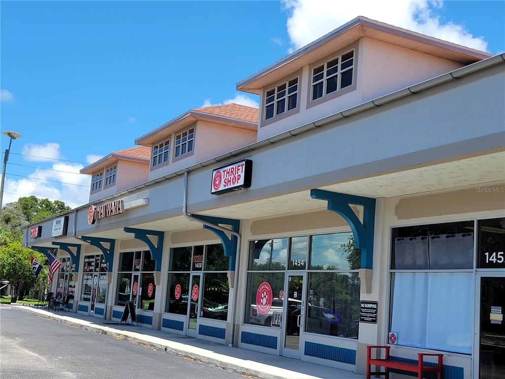 A row of commercial storefronts with a thrift shop and restaurant under a shared roof — 1454-1470 ALT 19 UNIT 1454-1470, PALM HARBOR, FL