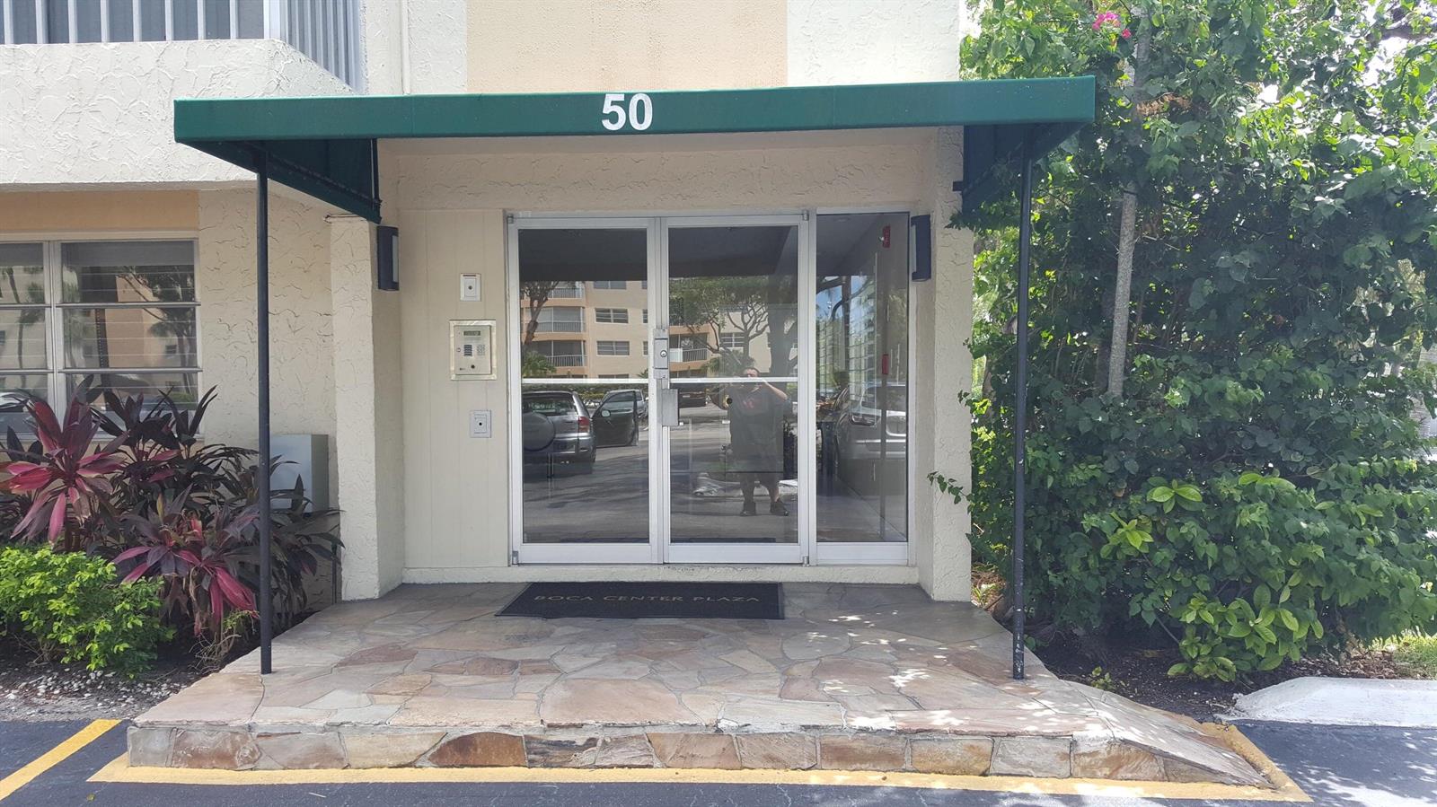 The exterior entrance of a building features a green awning, glass doors, and stone steps — 50 SW 3rd Avenue # 5080, Boca Raton FL 33432, BOCA RATON, FL