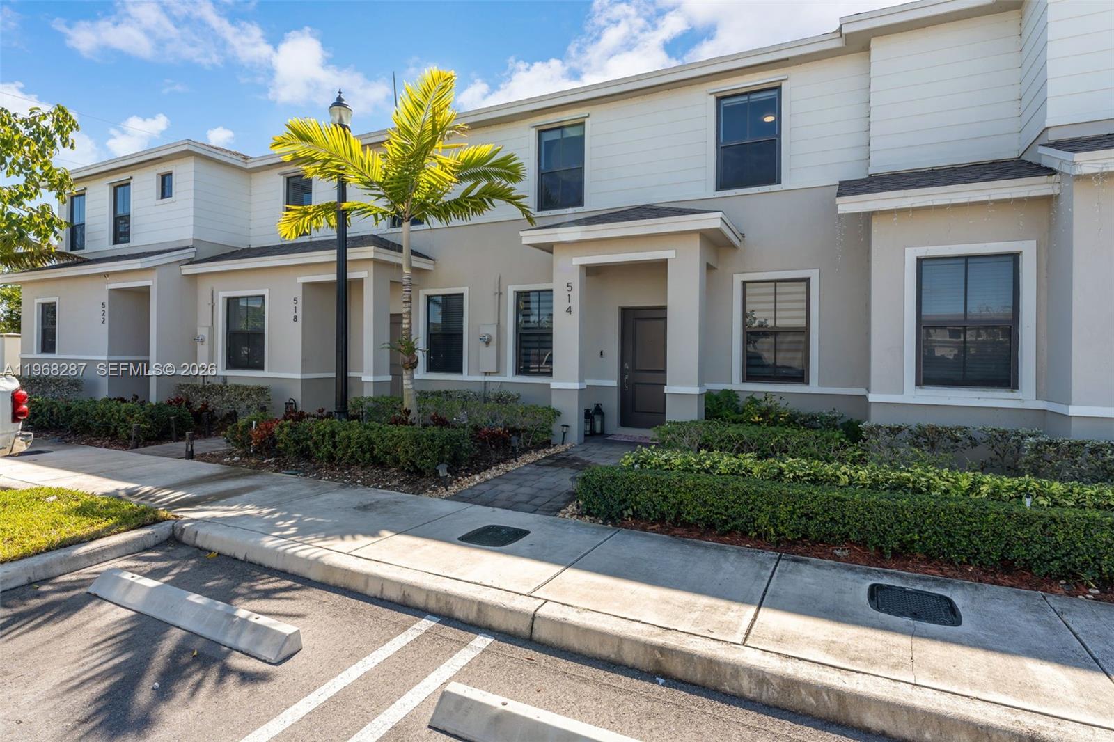 A row of two-story townhouses features beige stucco, white siding, and small front gardens — 514 NE 12th St, Florida City FL 33034, FLORIDA CITY, FL