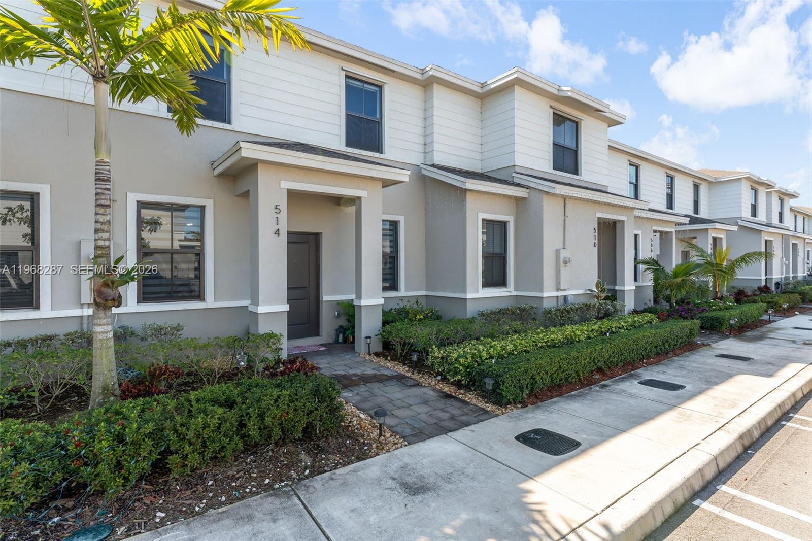 A row of two-story townhomes with beige stucco, white siding, and landscaped front walkways — 514 NE 12th St, Florida City FL 33034, FLORIDA CITY, FL