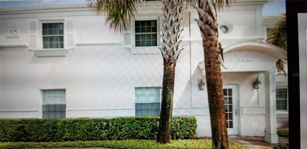 A white two-story building exterior features palm trees, a covered entrance, and a green hedge — 213 SEAHORSE DRIVE SE UNIT D, ST PETERSBURG, FL