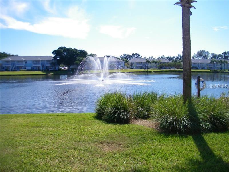A fountain sprays water in the center of a lake surrounded by apartment buildings — 213 SEAHORSE DRIVE SE UNIT D, ST PETERSBURG, FL