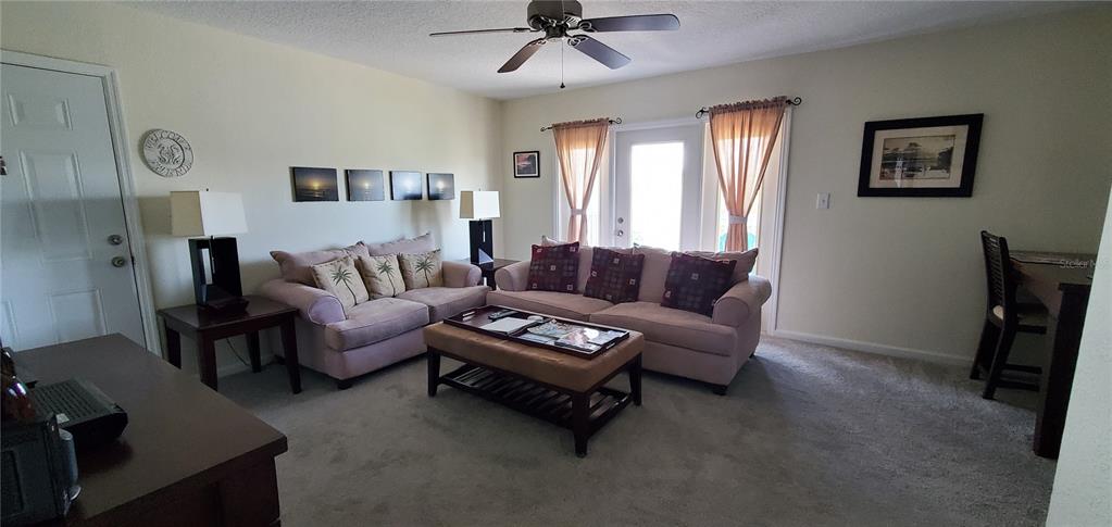 A living room features a beige sofa, a coffee table, and a ceiling fan — 213 SEAHORSE DRIVE SE UNIT D, ST PETERSBURG, FL
