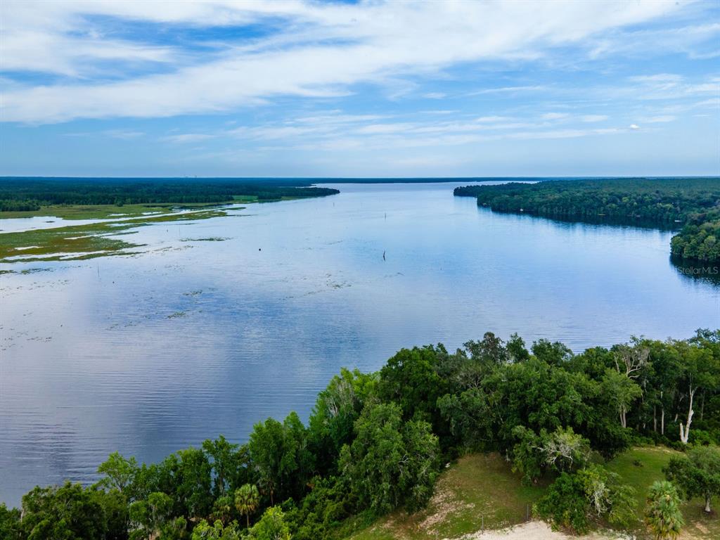 An aerial view shows a large lake bordered by dense forests and marshy shoreline — 15991 NE 243RD PLACE ROAD UNIT 32, FORT MC COY, FL