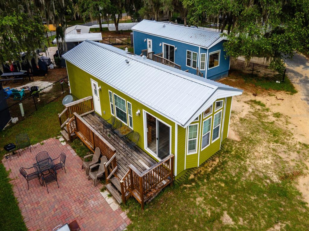 An aerial view of a green mobile home with a wooden deck and brick patio — 15991 NE 243RD PLACE ROAD UNIT 32, FORT MC COY, FL