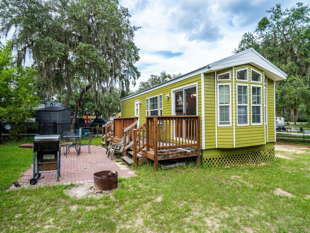 A lime green mobile home with a wooden deck and a brick patio with a grill — 15991 NE 243RD PLACE ROAD UNIT 32, FORT MC COY, FL