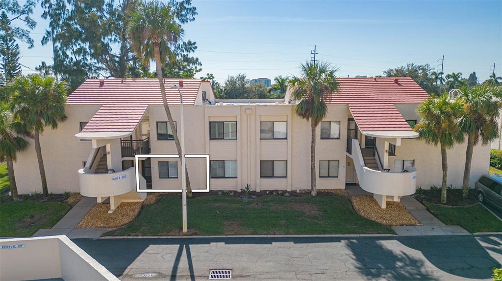 An exterior view of a two-story apartment building with a red tile roof and palm trees — 5510 PUERTA DEL SOL BOULEVARD S UNIT 132, ST PETERSBURG, FL