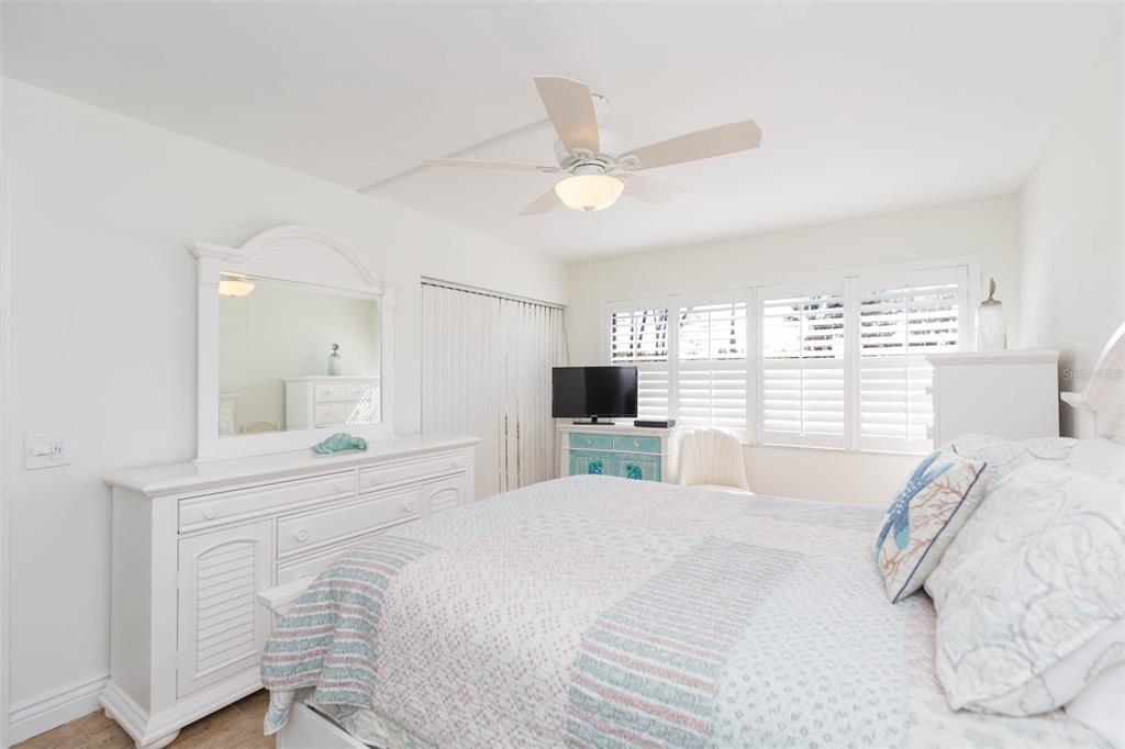 A bedroom features a white dresser with a mirror, a bed, and a ceiling fan — 5510 PUERTA DEL SOL BOULEVARD S UNIT 132, ST PETERSBURG, FL