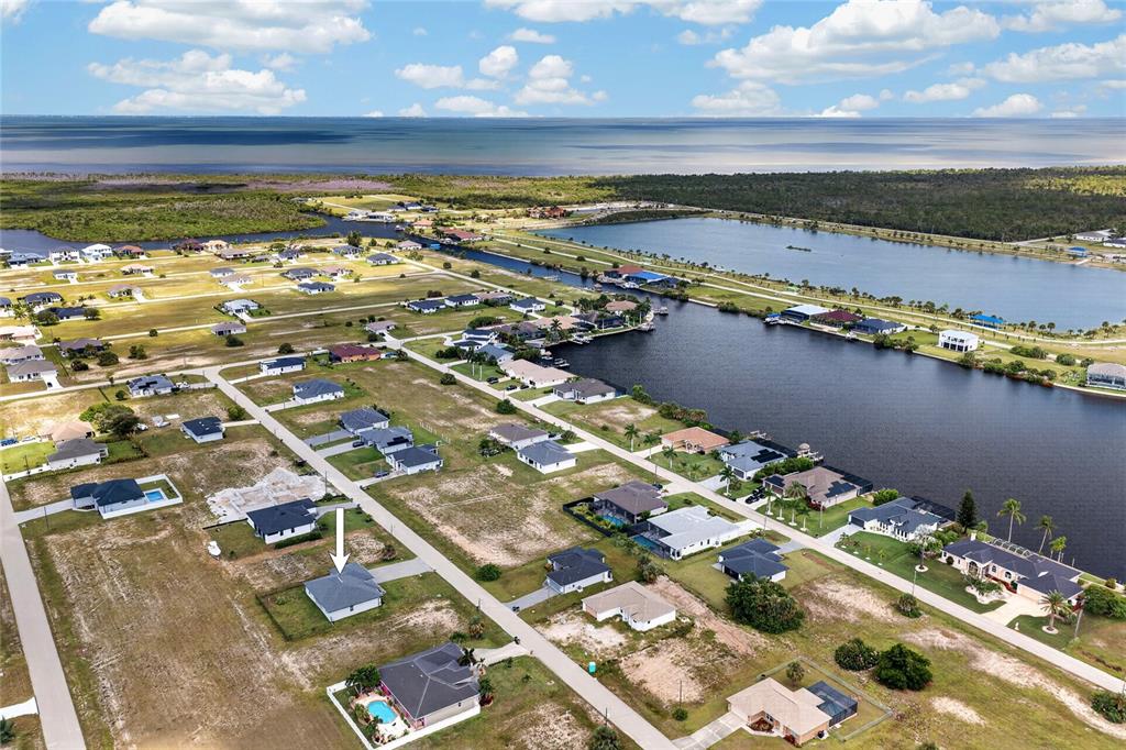 An aerial view shows a residential neighborhood with houses near a canal and large lake — 4238 NW 34TH LANE, CAPE CORAL, FL