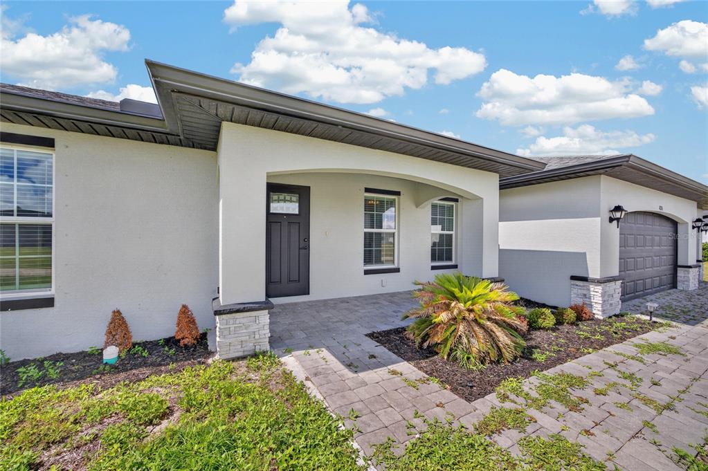 A single-story house exterior features a covered entryway, stone accents, and a paved driveway — 4238 NW 34TH LANE, CAPE CORAL, FL