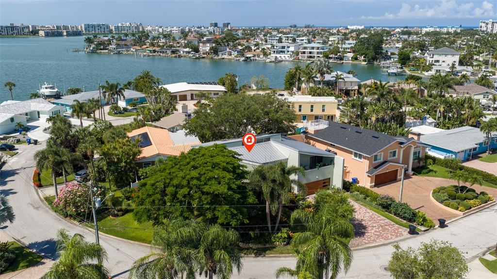 An aerial view shows a modern house with a metal roof surrounded by lush landscaping — 735 79TH CIRCLE S, ST PETERSBURG, FL