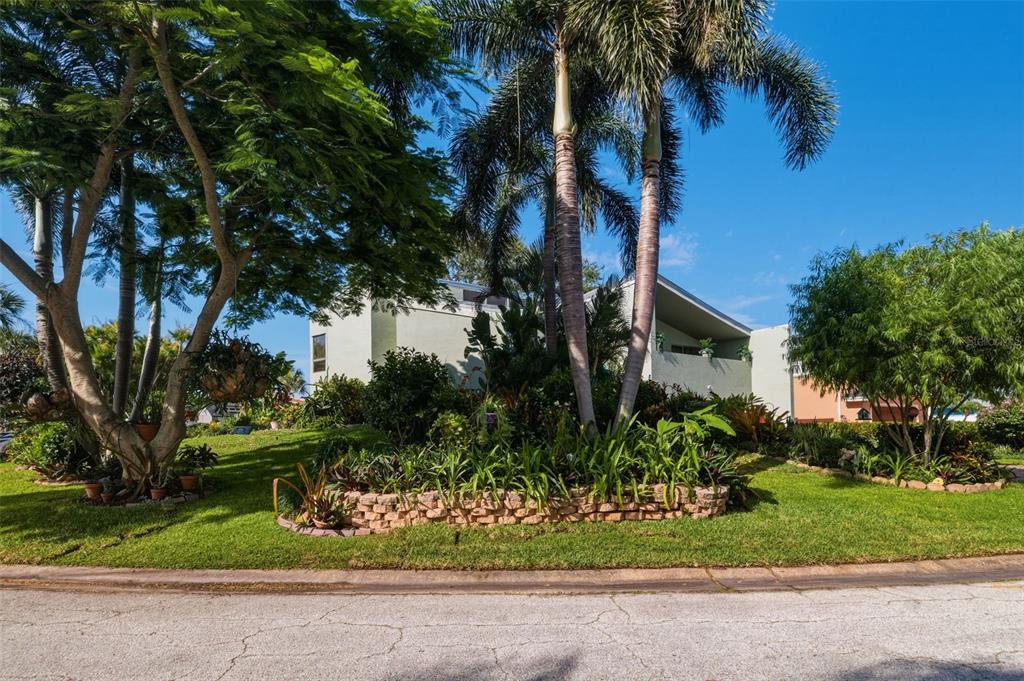 A two-story house with a sloped roof is surrounded by lush landscaping and tall palms — 735 79TH CIRCLE S, ST PETERSBURG, FL