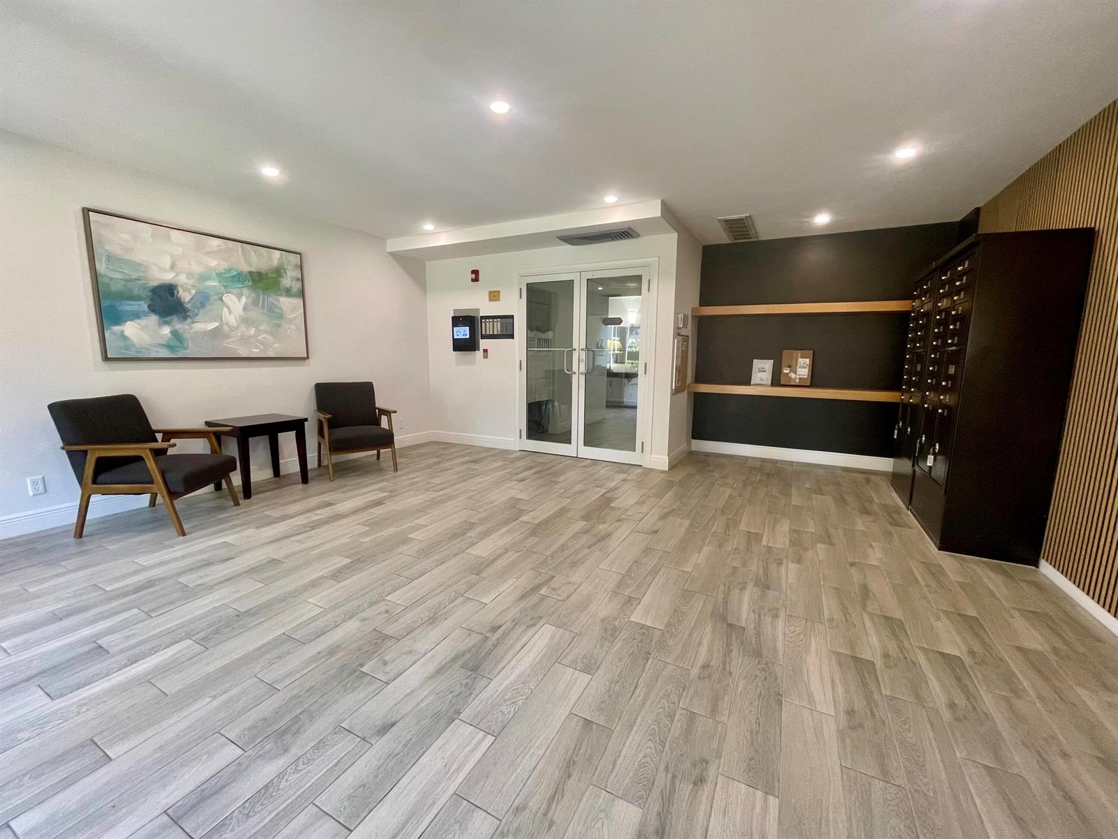 A lobby features wood-look tile flooring, two armchairs, a side table, and a mail station — 250 NE 20th Street # 3080, Boca Raton FL 33431, BOCA RATON, FL