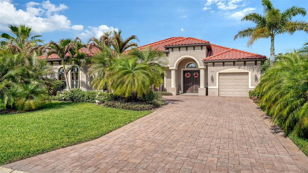 A single-story house with a red tile roof, beige stucco walls, and a paved driveway — 1043 145TH STREET CIRCLE NE, BRADENTON, FL