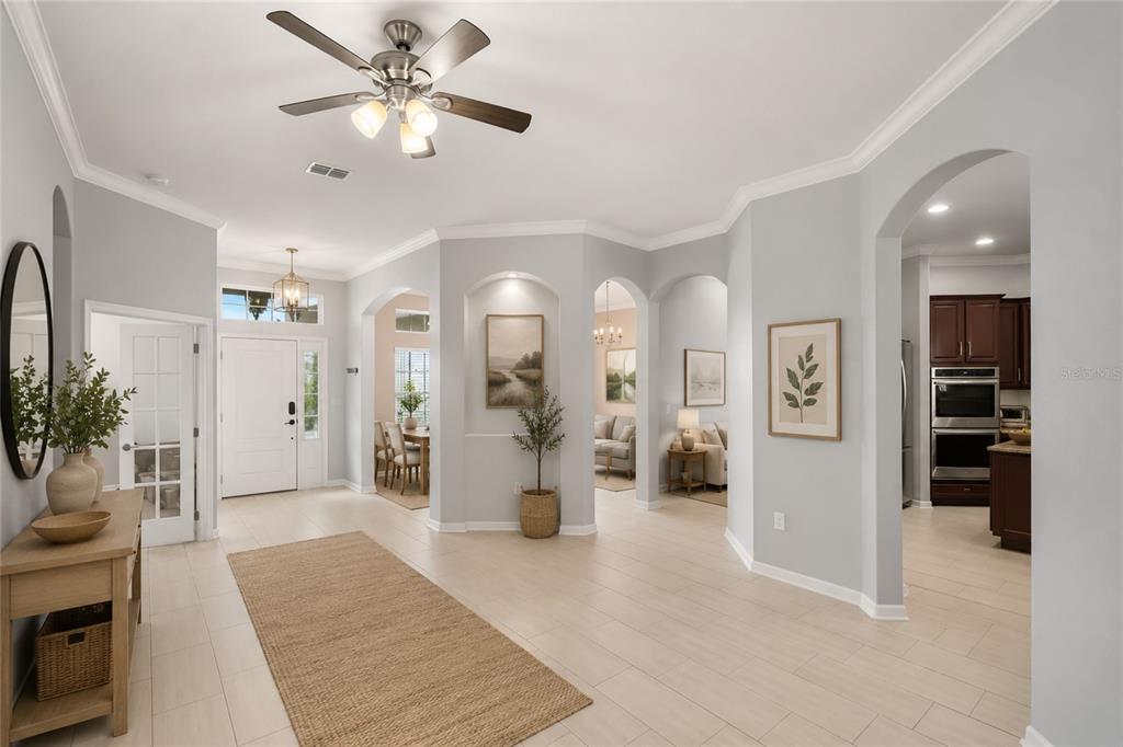 A bright, open-concept foyer features light tile flooring, arched entryways, and a ceiling fan — 410 SAUVIGNON WAY, GROVELAND, FL