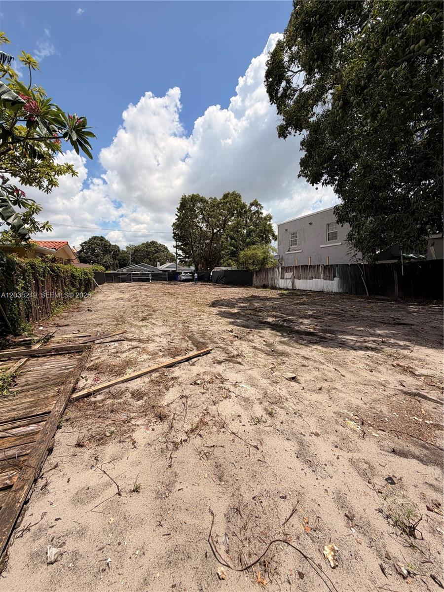 A vacant, sandy residential lot is enclosed by wooden fences and surrounded by mature trees — 2544 SW 17th St, Miami FL 33145, MIAMI, FL