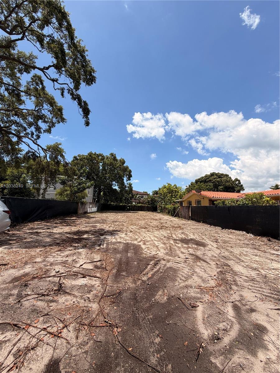 A vacant, cleared rectangular lot is enclosed by black fencing under a clear blue sky — 2544 SW 17th St, Miami FL 33145, MIAMI, FL
