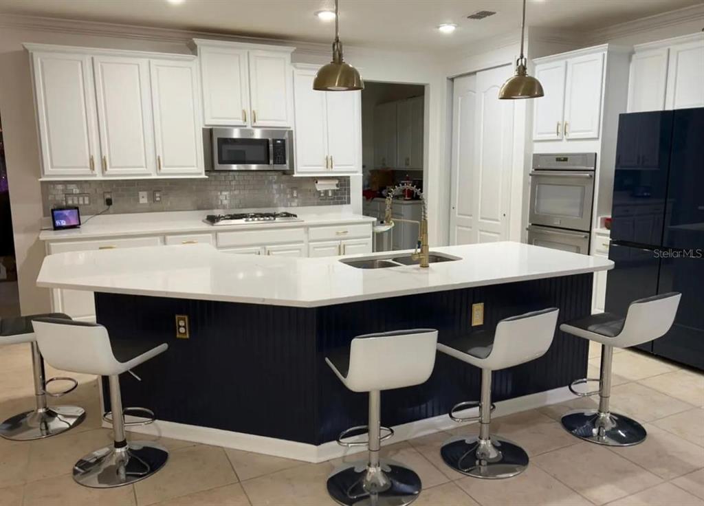 A kitchen features white cabinets, a dark blue island with bar seating, and stainless appliances — 36 PRIVADO COURT UNIT 36, ST AUGUSTINE, FL