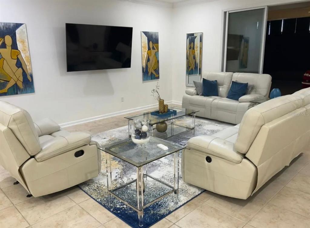 A living room features white leather reclining furniture, glass tables, and abstract wall art — 36 PRIVADO COURT UNIT 36, ST AUGUSTINE, FL