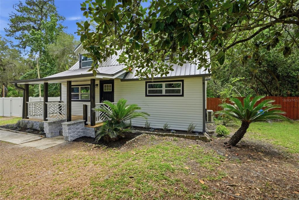 A white house with a metal roof and a front porch sits on a lawn — 14335 SNOW MEMORIAL HIGHWAY, BROOKSVILLE, FL