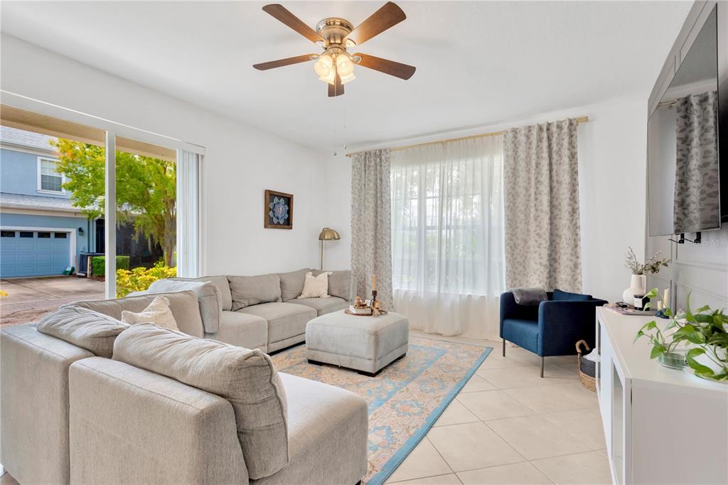 A living room features a gray sectional sofa, a blue armchair, and a ceiling fan — 8307 MANOR CLUB CIRCLE UNIT 1, TAMPA, FL