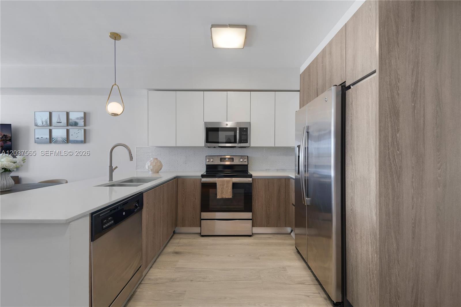 A modern kitchen features white upper cabinets, wood-grain lower cabinets, stainless steel appliances, and countertops — 1501 SW 37th Ave # 1307, Miami FL 33145, MIAMI, FL