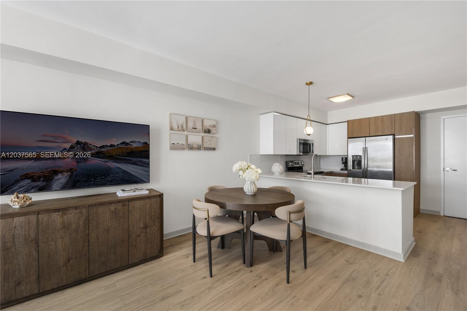 A dining area with a round table sits adjacent to a modern kitchen with white cabinets — 1501 SW 37th Ave # 1307, Miami FL 33145, MIAMI, FL