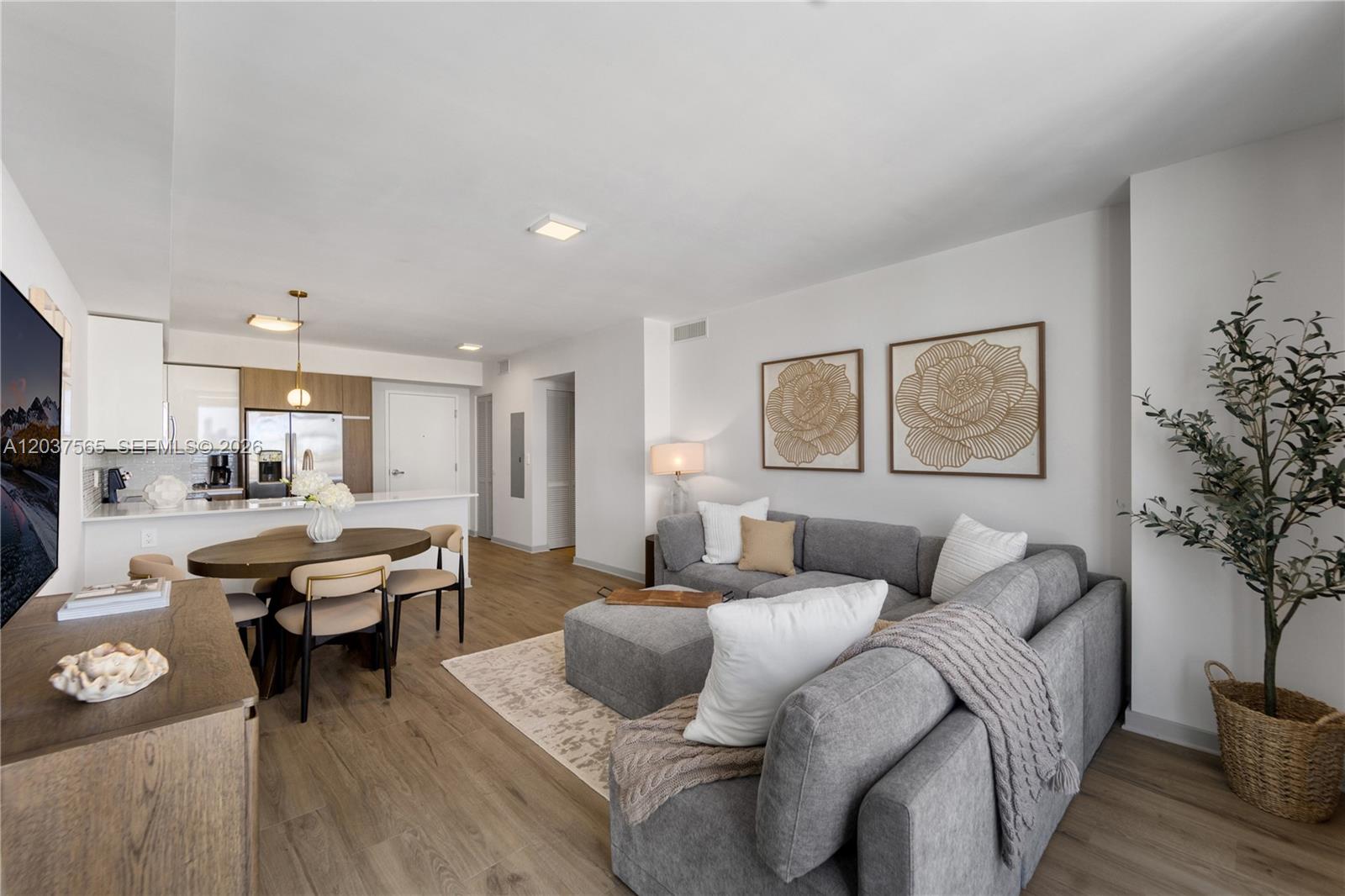 A modern living room and dining area feature a grey sectional sofa and wood flooring — 1501 SW 37th Ave # 1307, Miami FL 33145, MIAMI, FL