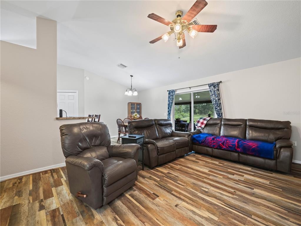 A living room features wood-look flooring, brown leather furniture, and a ceiling fan — 3500 HIBISCUS DRIVE, INDIAN LAKE ESTATES, FL