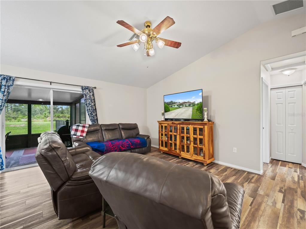 A living room features leather furniture, a wooden media console, and sliding glass patio doors — 3500 HIBISCUS DRIVE, INDIAN LAKE ESTATES, FL