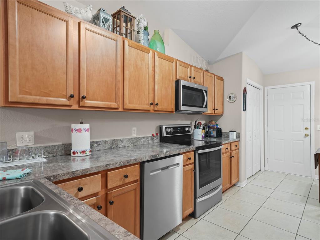 A kitchen features wood cabinets, stainless steel appliances, and gray laminate countertops — 3500 HIBISCUS DRIVE, INDIAN LAKE ESTATES, FL