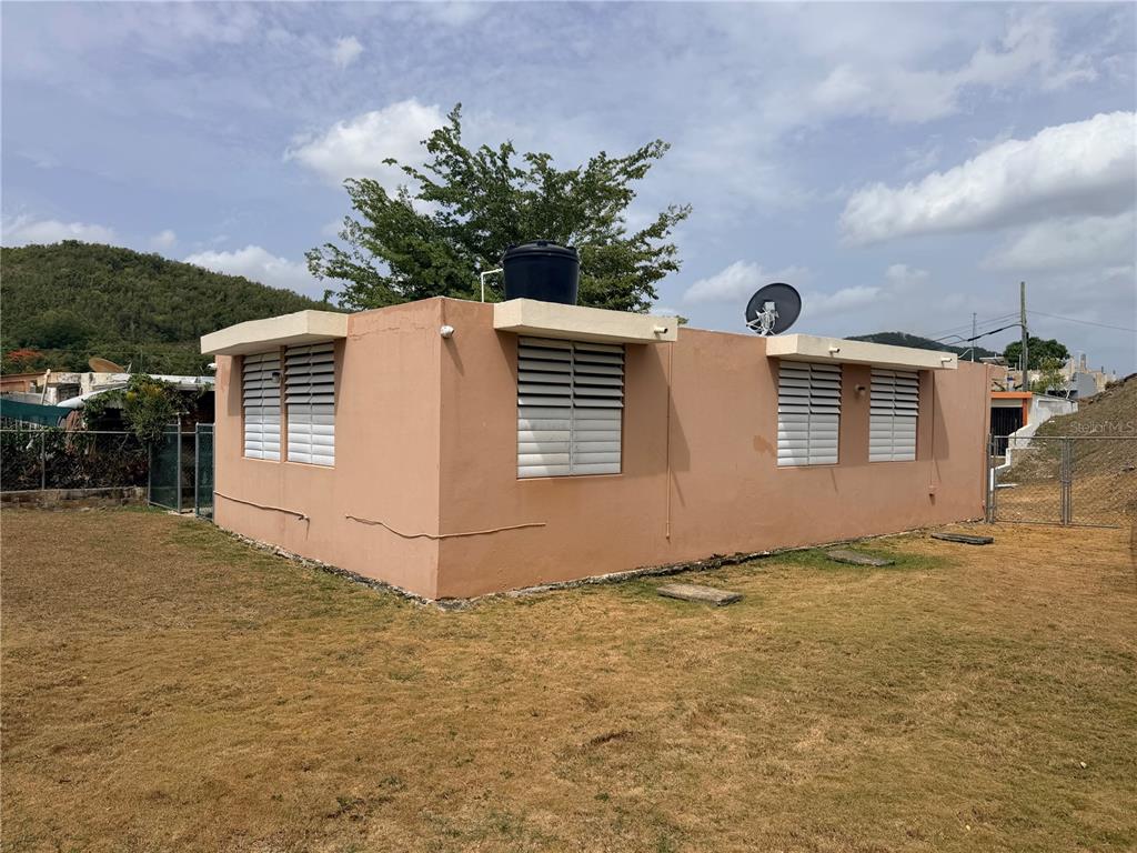A single-story peach-colored house with louvered windows and a rooftop water tank — 163 CALLE VALENCIA, SAN GERMAN, PR
