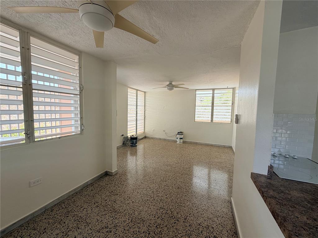 An empty room with terrazzo floors, two ceiling fans, and louvered windows — 163 CALLE VALENCIA, SAN GERMAN, PR