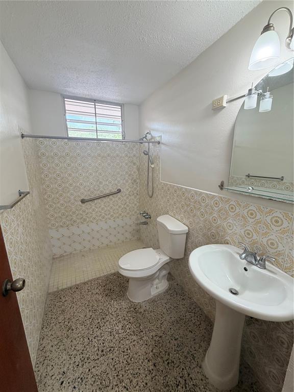A bathroom features a pedestal sink, a toilet, and a tiled shower area with a window — 163 CALLE VALENCIA, SAN GERMAN, PR
