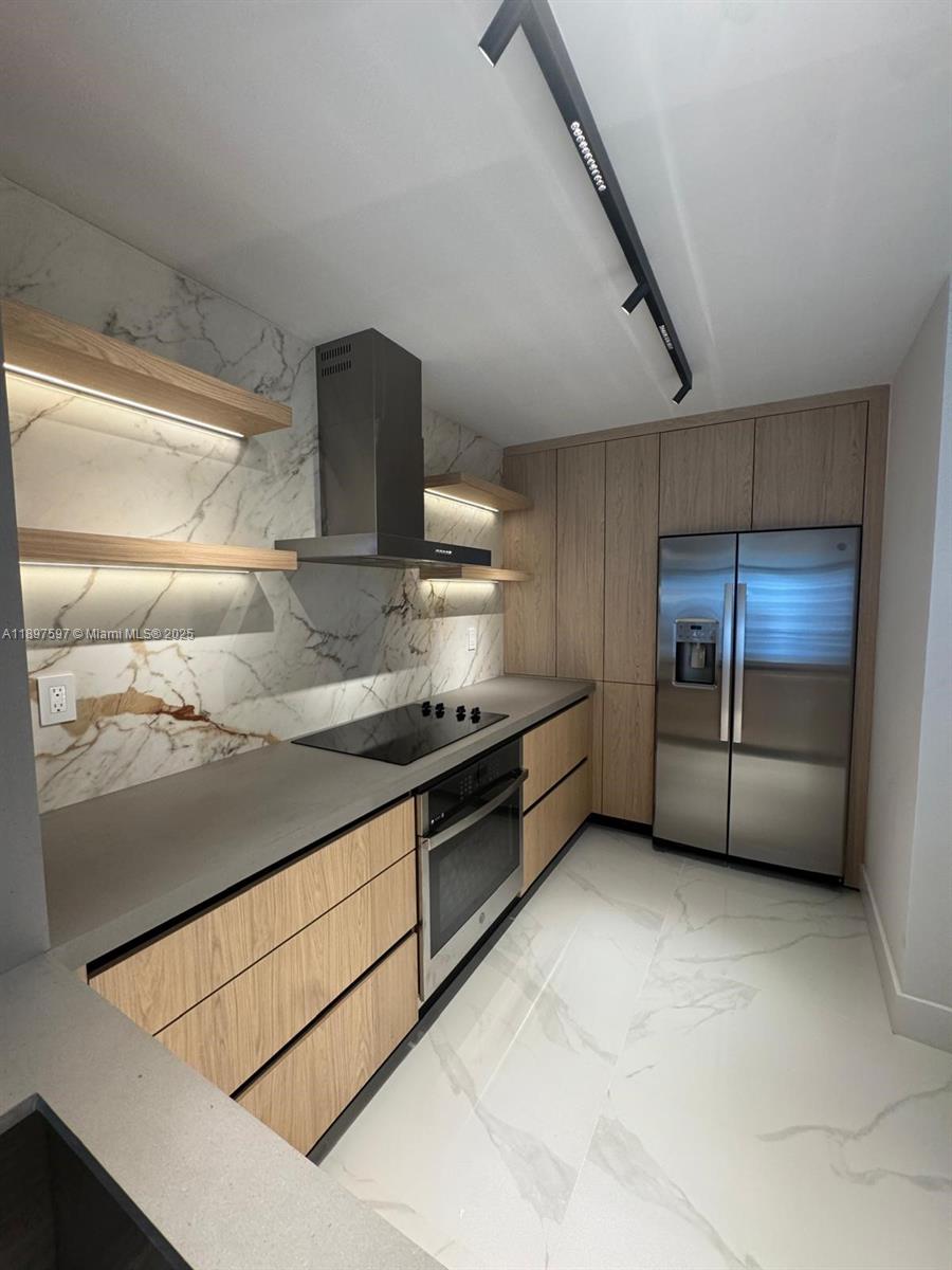 A modern kitchen features wood-grain cabinetry, marble-patterned walls, stainless steel appliances, and floating shelves — 800 N Miami Ave # 901, Miami FL 33136, MIAMI, FL
