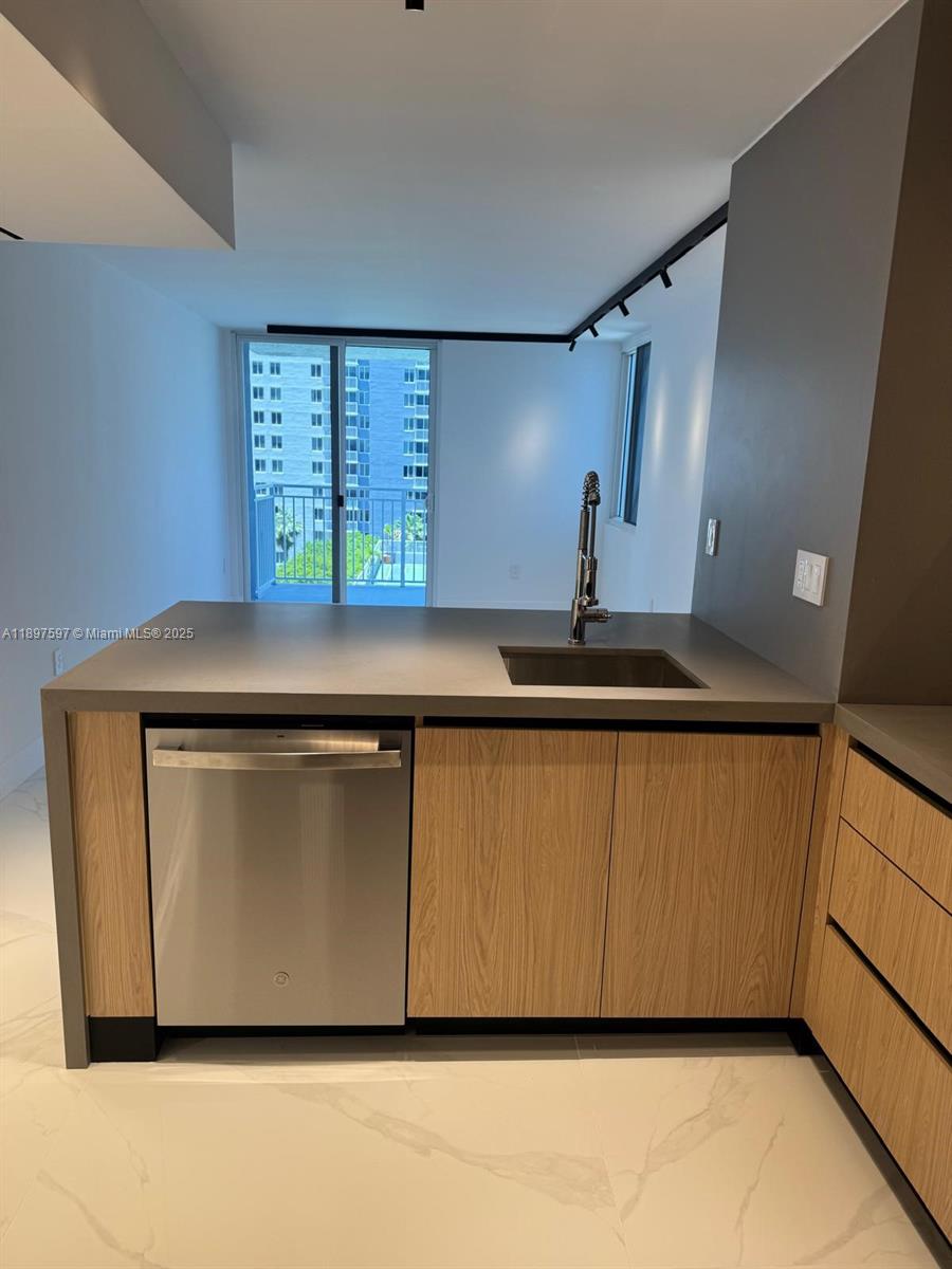 A modern kitchen features light wood cabinets, a stainless steel dishwasher, and a gray countertop — 800 N Miami Ave # 901, Miami FL 33136, MIAMI, FL