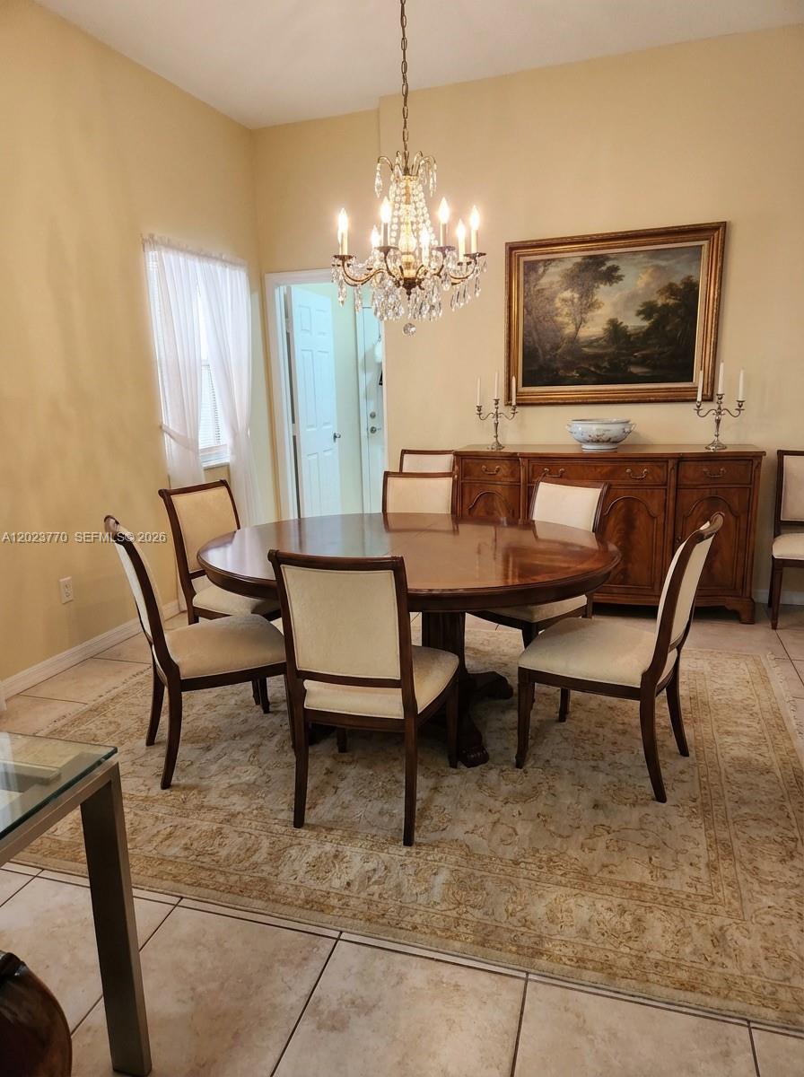 A dining room features a round wooden table, six chairs, a chandelier, and a sideboard — 2363 SE 19th St, Homestead FL 33035, HOMESTEAD, FL